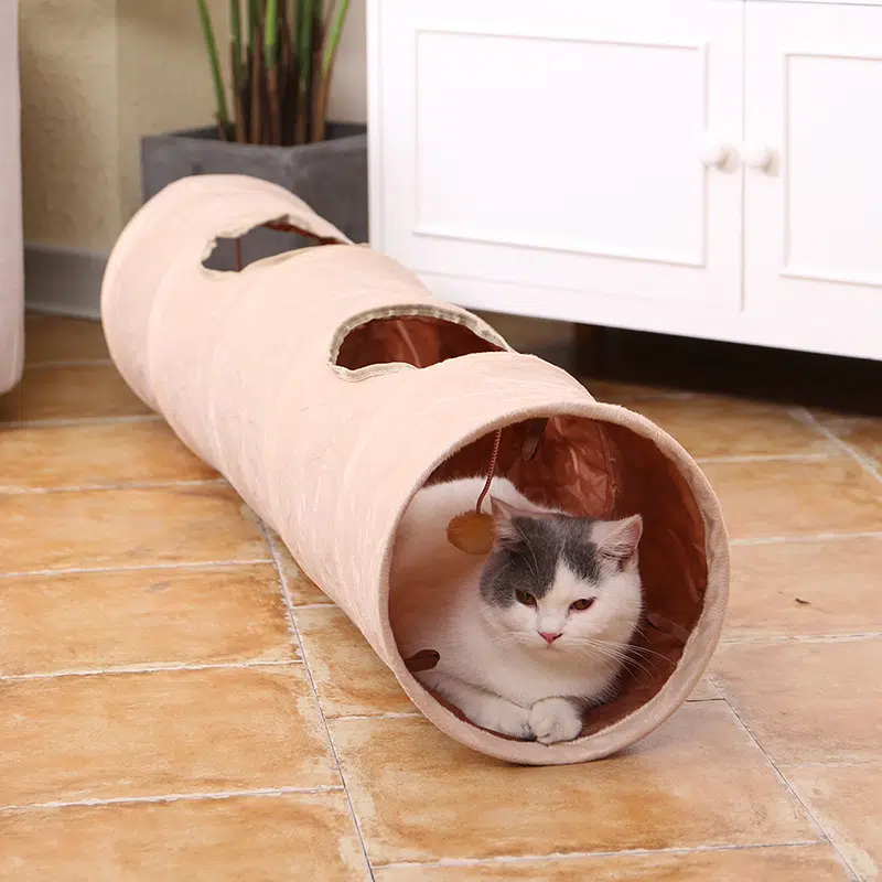 Tunnel long pliable en daim pour chat rose avec un chat à l'intérieur dans une maison