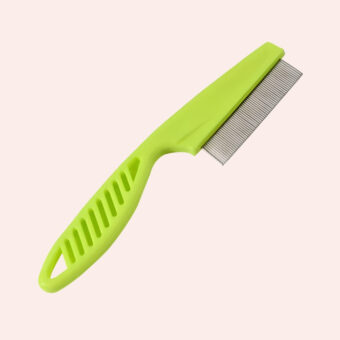 Brosse chat à points fins en acier inoxydable avec le manche vert. Sur fond rose pâle.