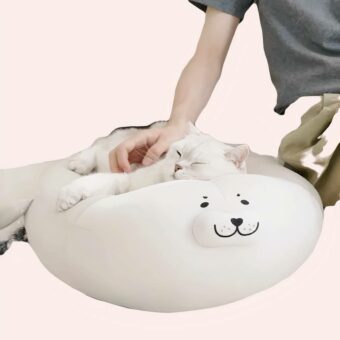 Coussin en peluche en forme de phoque pour chat blanc, confortable sur un tapis dans une maison