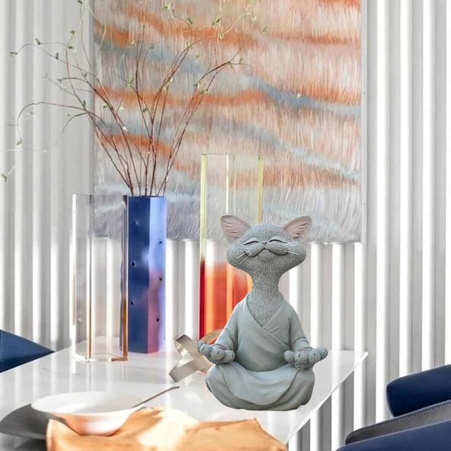 Statuette d'un chat qui médite. L'apparence fait penser à un dessin animé. Le chat est roux avec une tunique orange. Il est en position du Bouodha.
