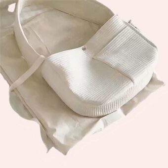 Sac à main respirant en toile pour transport chat blanc, confortable sur un lit dans une maison