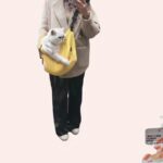 Sac de transport respirant et ouvert pour chat jaune, très confortable porté par une femme avec un chat à l'intérieur dans une magasin.