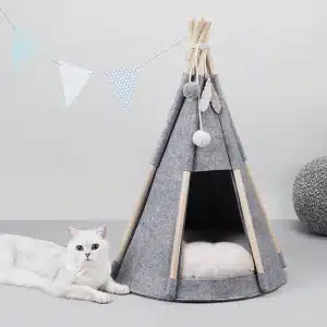 Tente grise qui sert de niche pour chat avec un chat blanc à côté