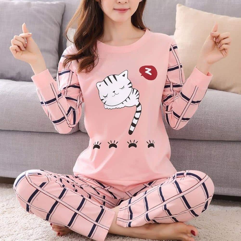 Femme assise en tailleur portant un pyjama rose illustré d'un petit chat amusant