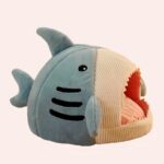 Une niche de couchage pour chat en forme de requin bleu avec une gueule beige et une langue rose sur fond blanc.