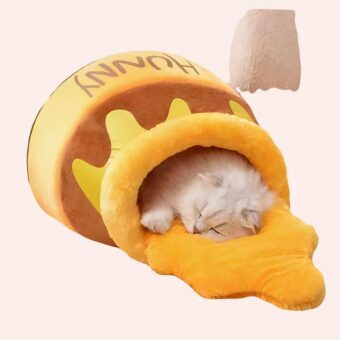 Une niche pour chat en forme de pot de miel jaune et marron avec un chat allongé dedans. La niche est posée sur le sol en parquet.