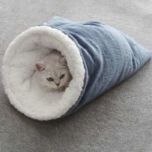 chatblanc se trouve dans un sac de couchage gris à l'extérieur, et blanc dedans, tout doux, posé sur de la moquette