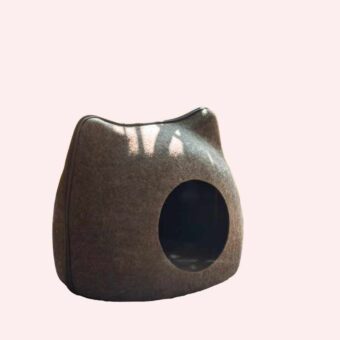 Lit pour chat mignon en forme d'œuf de couleur gris, posé sur du parquet devant un pot de plante