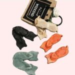 4 paire de pantoufles tong en forme de chat sont sur le sol. Elles sont de couleur noire, beige, verte, et orange