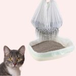 Un bac à litière équipé du lot de 7 sacs litière filtrante de voyage pour chat dont le sac filtrant supérieur est rempli de sable souillé et une tête de chat qui regarde au loin.