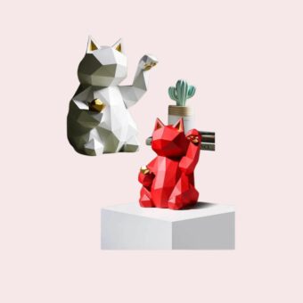 Une figurine de chat en céramique porte bonheur origami blanche et la même figurine en rouge positionnée en contrebas.