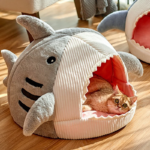 Un chat dormant dans son lit en forme de requin sur le sol