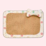Un tapis rafraichissant chat en fibre tressée à la main avec centre tissé, bordure colorée et petit coussin en forme d’os, posé sur fond rose clair.