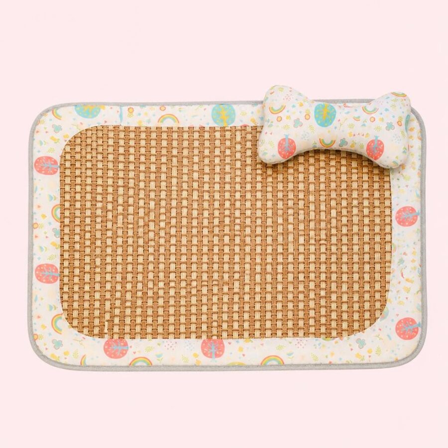 Un tapis rafraichissant chat en fibre tressée à la main avec centre tissé, bordure colorée et petit coussin en forme d’os, posé sur fond rose clair.