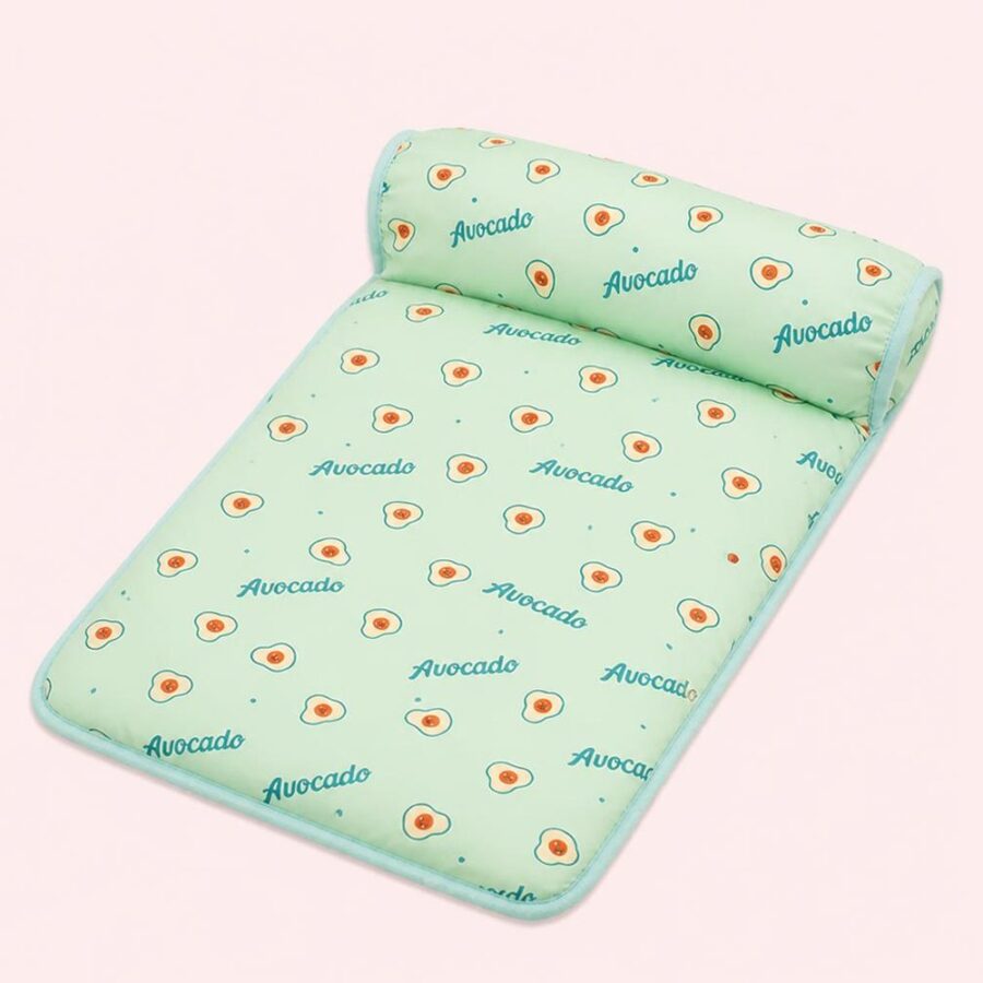 Un tapis rafraichissant chat en soie glacée pour dissiper la chaleur vert menthe, avec un motif d’avocats, posé sur un fond rose clair.